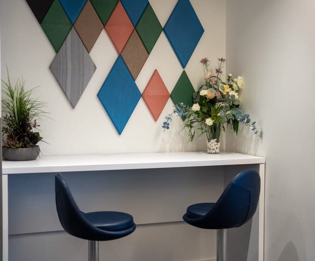 Bar-height seating and fresh flowers beside a geometric accent wall