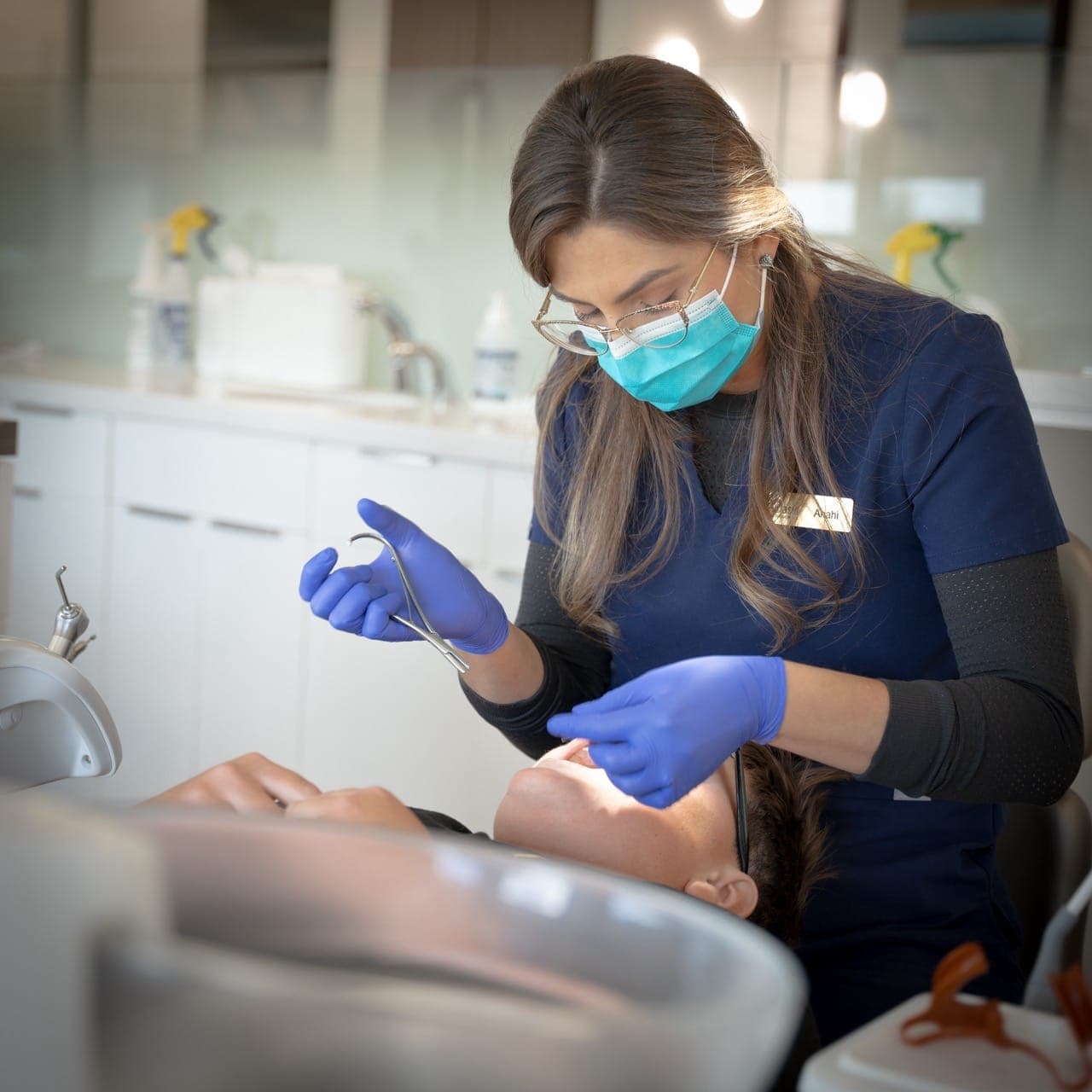 Orthodontic assistant in protective gear working with a patient in the treatment area