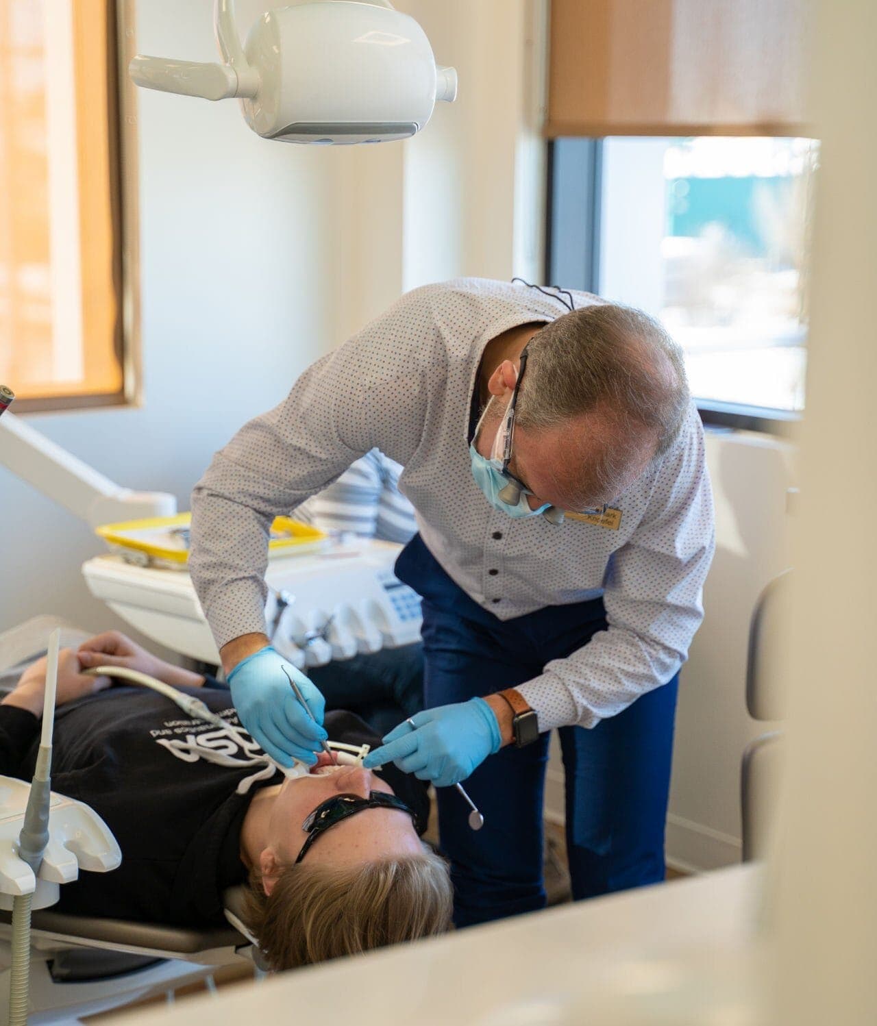 Orthodontist treating a teenage patient in the treatment chair