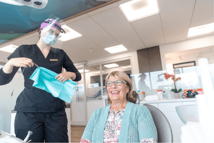 Smiling patient in the treatment chair as a team member prepares for the visit