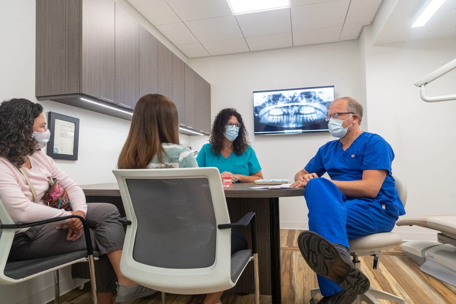 An orthodontist at Oasis Orthodontics talking a family through an x-ray at the consultation table
